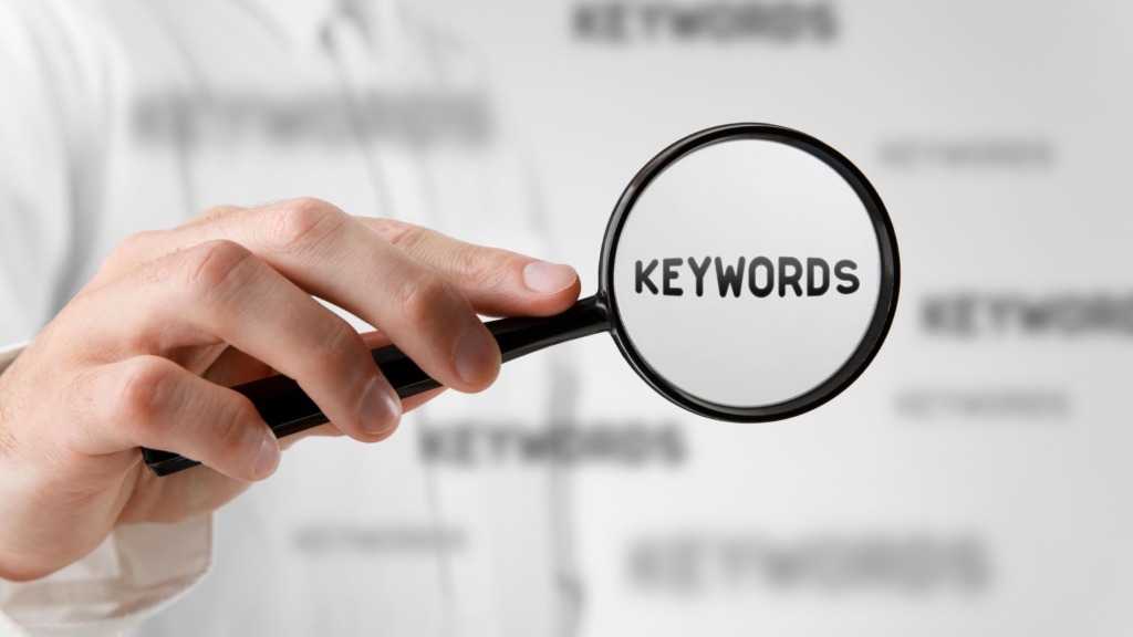 Person holding magnifying glass with KEYWORDS inside it